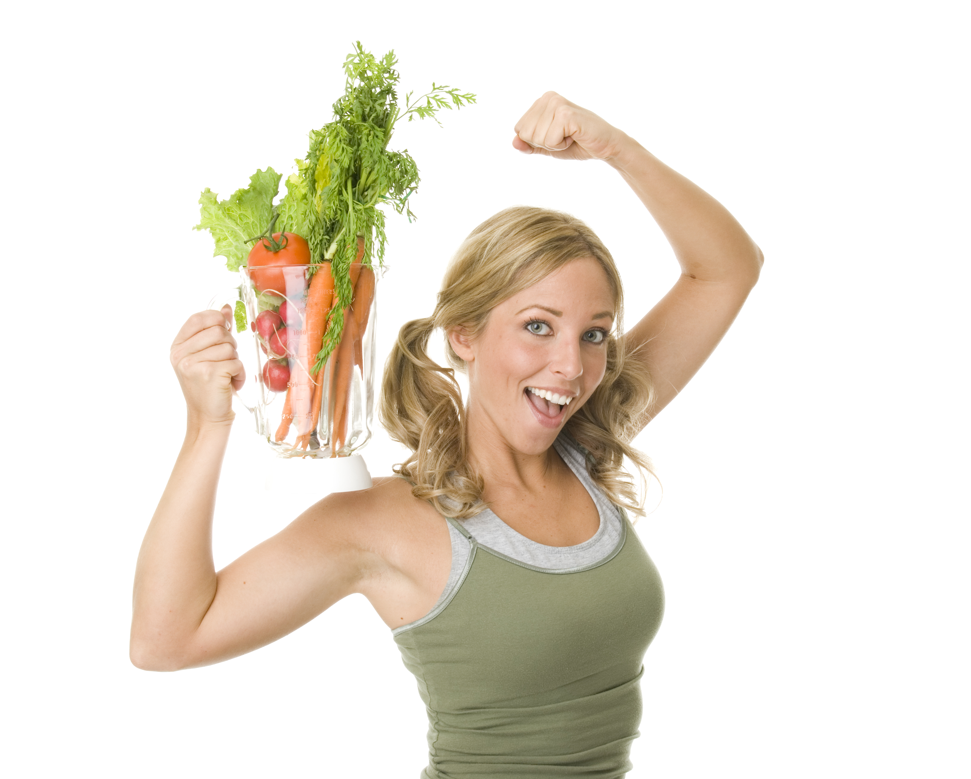 "A young, fit woman holds a blender full of vegetables while flexing her other arm."